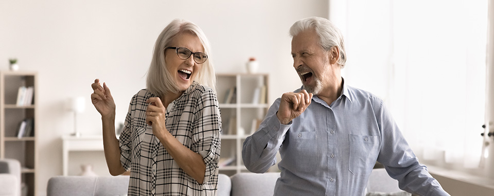 Et ældre ægtepar danser muntert i stuen